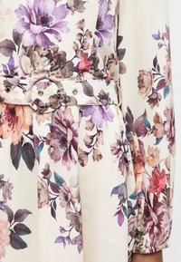 Φόρεμα με λουλουδάτο σχέδιο σε αποχρώσεις μωβ, ροζ και καφέ, με ζώνη από το ίδιο ύφασμα και στρογγυλό αγκράφα στη μέση.