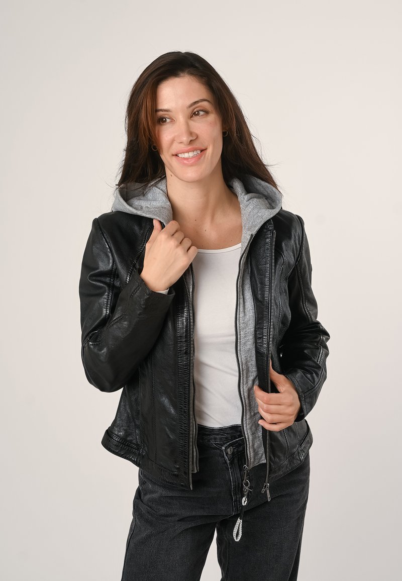 Zwarte leren jas met een grijze hoodie voering, ritsluiting en zijzakken, gedragen over een wit shirt en donkere jeans. Gladde textuur.