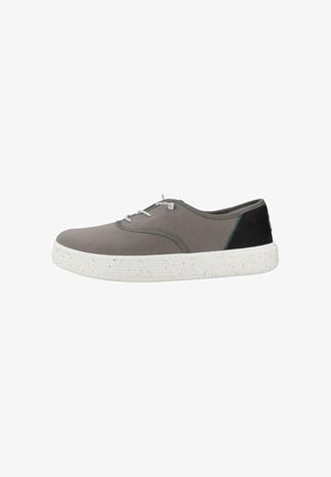 Zapatilla casual gris de corte bajo con suela blanca moteada y parche negro en el talón, con cordones blancos y detalles de costura mínimos.