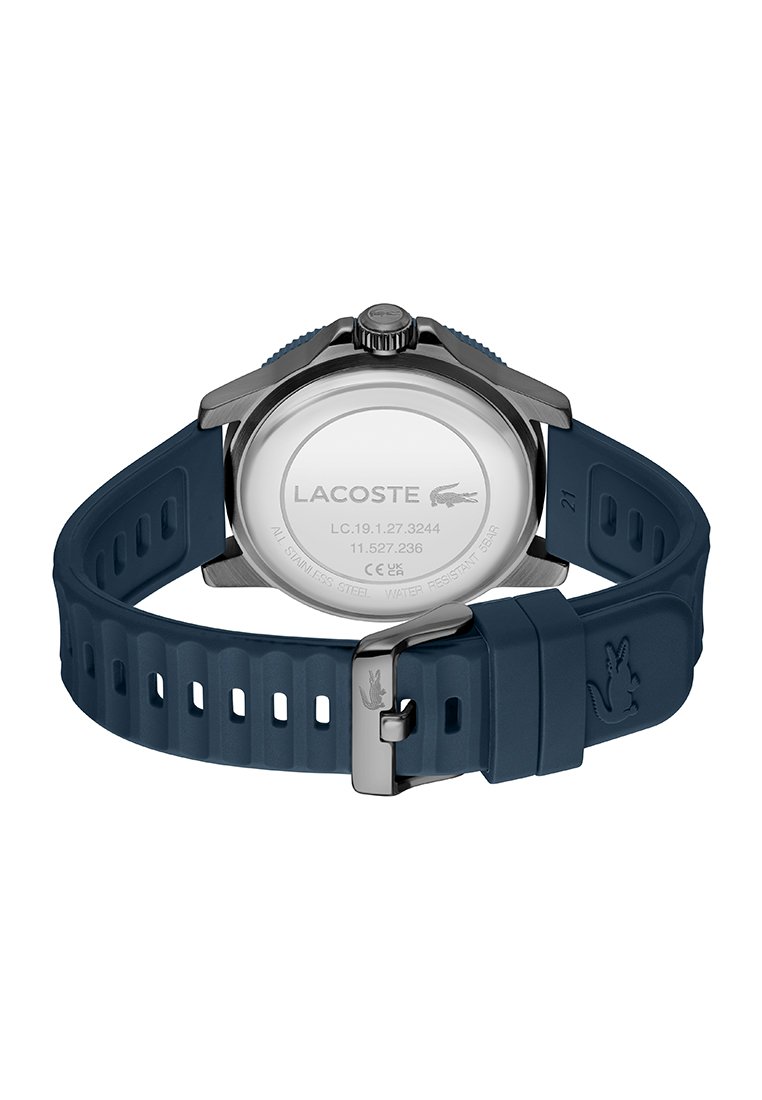 Vue arrière d'une montre Lacoste avec un bracelet en silicone bleu et un boîtier en acier inoxydable, montrant les détails du logo et de la boucle.