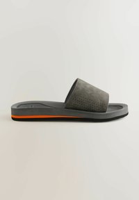Harmaa liukuva sandaali, jossa on rei'itetty yläosa, musta kumipohja ja oranssi korostusraita alareunassa.