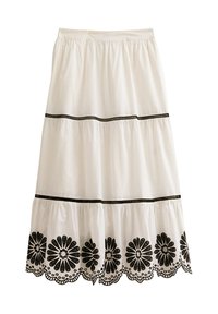 Witte katoenen rok met een gelaagd ontwerp, voorzien van zwarte geborduurde bloempatronen aan de onderrand en decoratieve zwarte biesbanden.