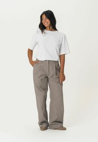 White short-sleeve t-shirt paired with brown, loose-fitting trousers. Pants have side pockets and a smooth texture. Simple design, neutral colors.