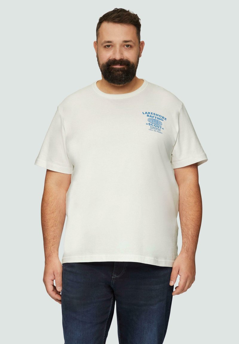 Witte katoenen t-shirt met korte mouwen, ronde halslijn en blauwe bedrukte tekst. Gecombineerd met donkere denim jeans.