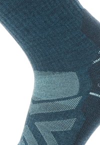 Blå och turkosa stickade strumpor med ett geometriskt mönster, ribbad yta och vadderade områden för komfort och stöd.