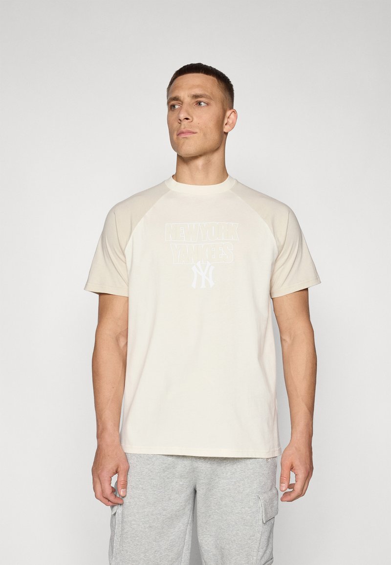 Beige bomull t-skjorte med korte raglan ermer, med et hvitt New York Yankees motiv på forsiden. Slett tekstur, rund hals.