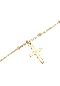 Bransoletka na łańcuszku w odcieniu złota z prostym zawieszką w kształcie krzyża z wybitym napisem "925", wykonana ze srebra sterling, teksturowane ogniwa.