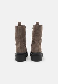 Bottines en suede marron avec un léger talon, fermetures éclair à l'arrière et languettes de tirage. Semelles en caoutchouc noir lisse pour une meilleure adhérence. Design minimaliste.