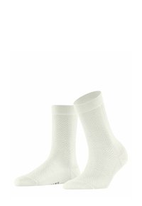 Chaussettes blanches avec un motif chevron, texture douce, bords côtelés et profil bas. Présente un logo de marque subtil sur la semelle.