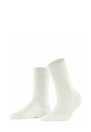 Chaussettes blanches avec un motif chevron, texture douce, bords côtelés et profil bas. Présente un logo de marque subtil sur la semelle.