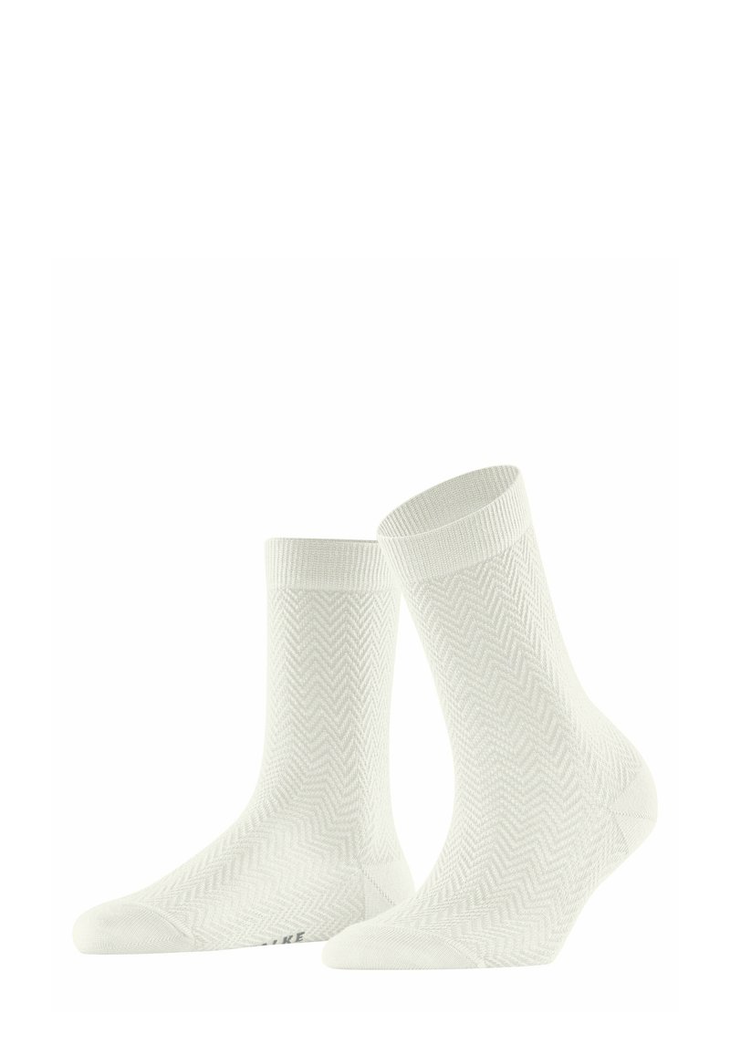 Chaussettes blanches avec un motif chevron, texture douce, bords côtelés et profil bas. Présente un logo de marque subtil sur la semelle.