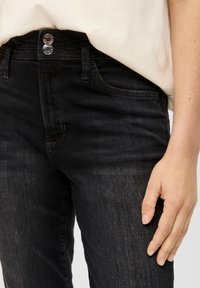 Zwarte denim jeans met een klassieke vijf-pocket ontwerp, twee knoopsluitingen en lichte vervagingdetails op de benen.