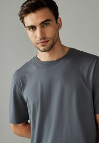 Grå kortærmet t-shirt med rund halsudskæring, lavet af glat bomuldsstof, med afslappet pasform og minimalistisk design.