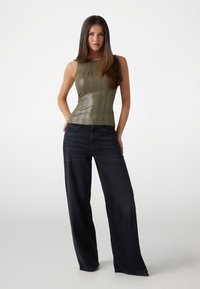 Olive green ribbed sleeveless top paired with wide-leg dark jeans. Top features a textured finish; jeans have a classic five-pocket design.