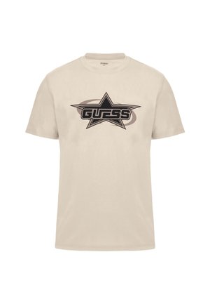 Bež pamučna majica s crnom grafikom zvijezde i riječju "GUESS" u podebljanim slovima. Kratki rukavi, okrugli izrez i glatka tekstura.
