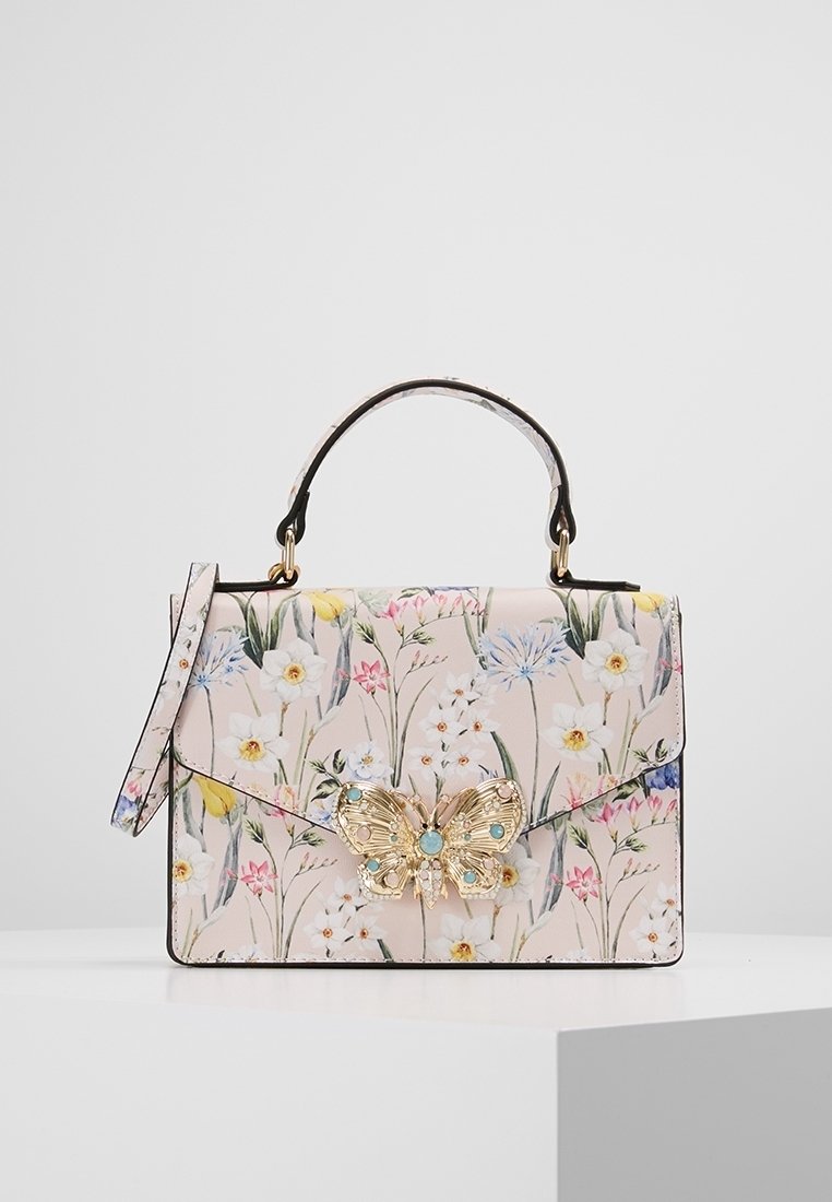 Blomstermønstret håndtaske i pink med en guldbutterfly-detalje på låget, sort kant og en aftagelig skulderrem.