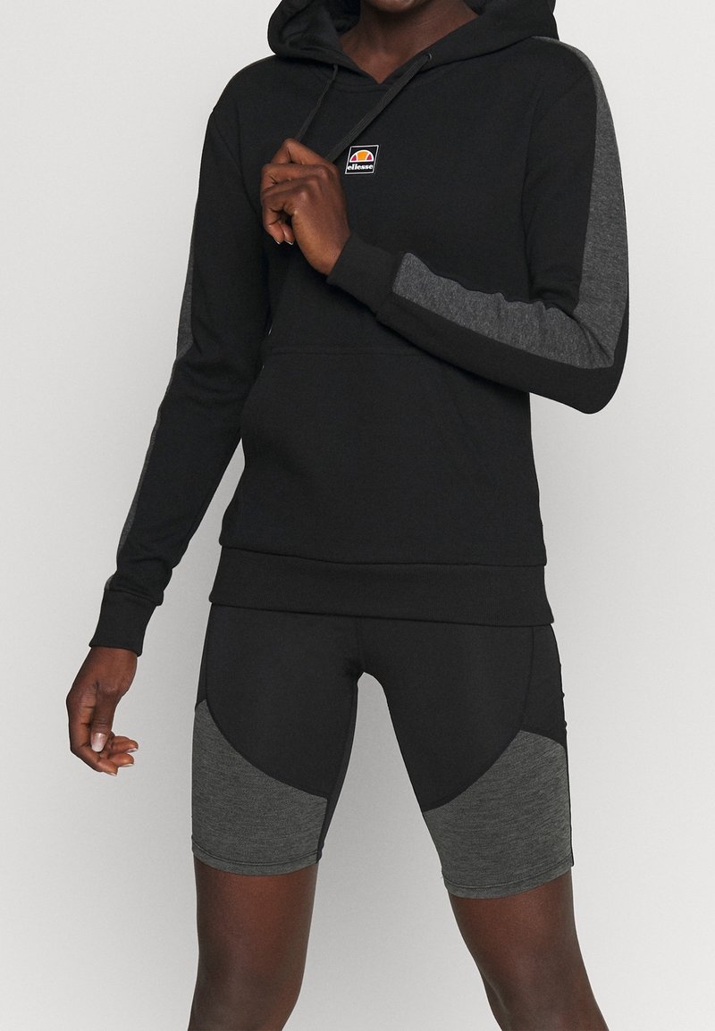 Sweat-shirt à capuche noir avec des accents gris sur les manches, associé à un short noir avec des panneaux gris sur les côtés. Tissu doux et coupe ajustée.