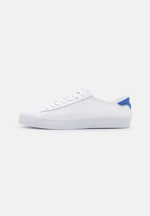 Białe niskie buty sportowe z siateczkową teksturą, białymi sznurówkami, gumową podeszwą i niebieskim akcentem na pięcie na jednolitym jasnym tle.
