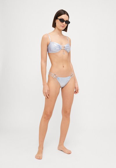 Gaiši zils bikini ar spīdīgu audumu, ar savērptu augšdaļu un zvaigžņu rotājumiem uz apakšdaļas. Regulējamas siksniņas, gluda tekstūra.