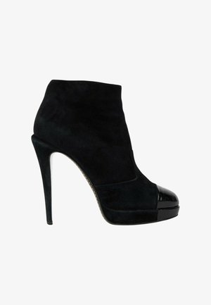 Bottine en daim noir avec talon haut stilettos et bout rond noir brillant avec semelle plateforme.