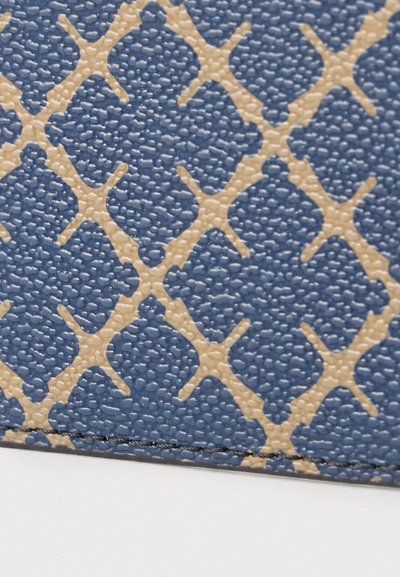 Υφασμάτινο μπλε με ανάγλυφο σχέδιο σε μπεζ ρόμβους. Η επιφάνεια είναι ελαφρώς ανυψωμένη, με ορατό ράμμα κατά μήκος της άκρης.