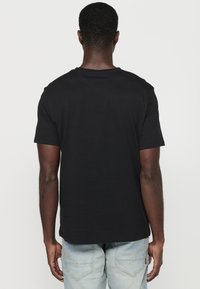 Černé tričko s krátkým rukávem a kulatým výstřihem, vyrobené z hladké bavlny. Má rovný lem a minimalistický design bez ozdob.