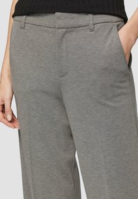 Pantalon gris en tissu texturé, avec une coupe droite, des poches avant et des passants de ceinture. Aucun motif ou accent visible.