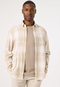 Langdurig mouw shirt in beige met een textuur gebreide onderlaag. heeft knoopsluiting, zak en een ontspannen pasvorm.