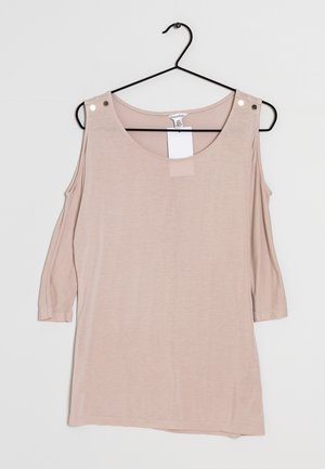 Haut rose clair à épaule dénudée avec des manches trois quarts. Fabriqué en tissu doux, il possède un col arrondi et deux accents métalliques sur les épaules.