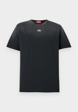Camiseta de algodón negra con cuello redondo, corte holgado, mangas cortas y un pequeño logo plateado en el pecho. Textura suave, diseño minimalista.