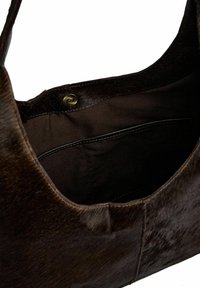 Barna bőr kézitáska sima, texturált felülettel. Bélése szövettel van ellátva, és réz patentzárral rendelkezik. A belsejében oldalzseb található.