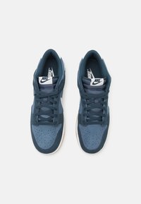 Nike tenisice s tamnoplavim gornjim dijelom od antilopa i mrežaste tkanine, bijelim logotipom i gumiranim potplatom. Perforirani vrh za ventilaciju.