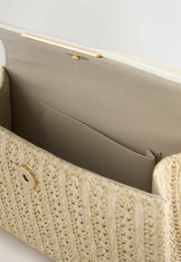 Sac à main en paille tressée avec un extérieur beige, doté d'un fermoir doré et d'une doublure en tissu beige doux, comprenant une poche intérieure pour l'organisation.