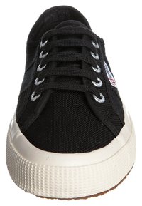 Sneaker nera in tela con punta tonda, suola in gomma bianca e sei occhielli metallici. Caratterizzata da lacci piatti neri e un piccolo dettaglio del logo.