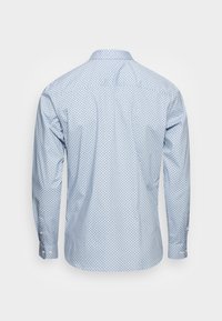 Lichtblauw shirt met lange mouwen en een klein donkerblauw gestippeld patroon, met knoopmanchetten, achterpas en een afgeronde zoomlijn. Gladde stoftextuur.