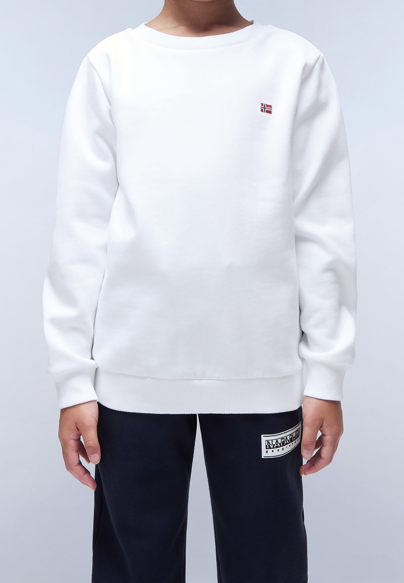 Enfant portant un sweat-shirt blanc avec un petit drapeau norvégien et un pantalon noir avec un patch logo Napapijri.