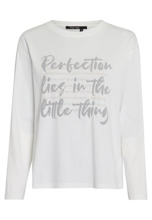 White long-sleeve shirt with grey text reading "Perfection lies in the little thing" in large cursive font on the front.