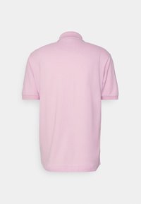 Polo rose à manches courtes avec un col côtelé et un ourlet droit, fabriqué en tissu lisse et léger. Aucun motif ni accent visible.
