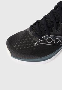 Černá sportovní obuv s texturovaným síťovým svrškem, elegantního designu, černými tkaničkami a bílou a šedou gumovou podrážkou.