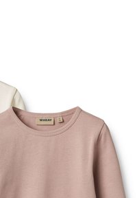 Közelkép bordázott kötött hosszú ujjú felsőkről bézs és törtfehér színekben, kerek nyakkivágással és Wheat márkajelzésekkel.