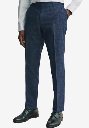 Pantalons pour hommes bleu marine en tissu texturé, dotés d'un design à coupe droite, pli à l'avant et chaussures de ville noires.