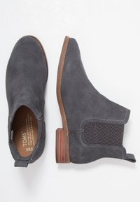 Botines de ante gris con un tacón bajo apilado, paneles laterales elásticos y una cinta para facilitar su uso. El interior presenta una plantilla de marca.