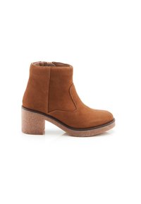 Bottine en daim marron avec un bout arrondi, un panneau élastique sur le côté et un talon épais texturé. Doublure intérieure lisse et profil élégant.