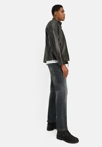 Czarna skórzana kurtka, szare dżinsy o wyblakłym kolorze oraz czarne botki za kostkę. Prosta biała koszulka pod kurtką, o dopasowanym kroju.