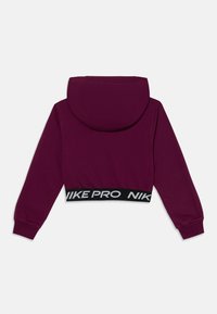 Krótkia bluza z kapturem w ciemnofioletowym materiale z czarną elastyczną talią, na której widnieje białe napisy "NIKE PRO", oraz z regulowanym kapturem.