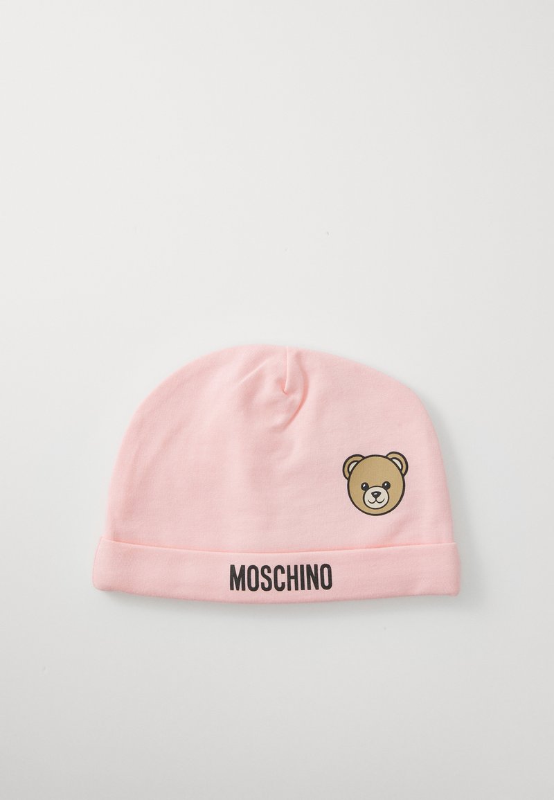 Světle růžová dětská čepice s ohnutým lemem, černý text "MOSCHINO" a malý grafický motiv medvídka na boku.