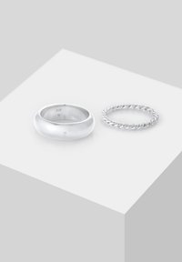 Zwei Silberringe: der eine ist ein glatter Band mit abgerundeter Form, der andere hat ein gewundenes Design. Beide sind mit "925" für Sterlingsilber gekennzeichnet.