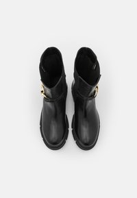 Botines de cuero negro con una superficie lisa, paneles laterales elásticos y un hebilla de acento dorado en el lateral exterior.