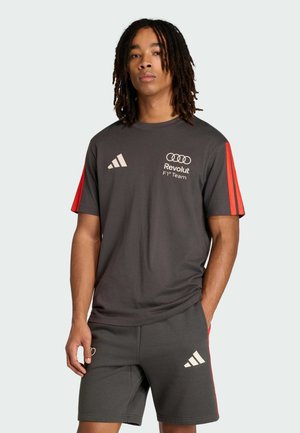 Maglietta sportiva grigia con strisce rosse sulle spalle, con logo Adidas e marchio Audi. Abbinata a pantaloncini grigi coordinati, sempre firmati Adidas.
