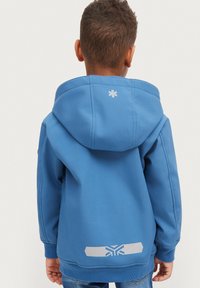 Blaues Kapuzensweatshirt aus strukturiertem Stoff. Verfügt über ein weißes Logo im oberen Rückenbereich und reflektierende Akzente am unteren Saum.
